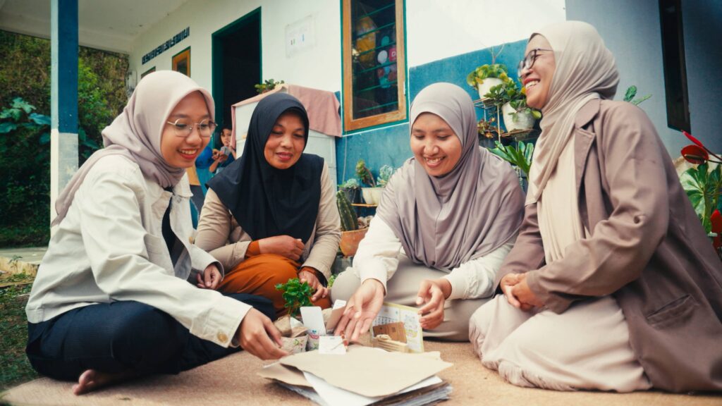 Women of BenihBunbun sitting, smiling around planting products