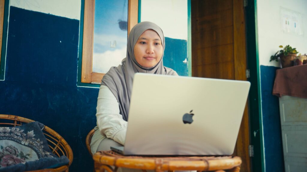 Azifah sitting and looking at a laptop