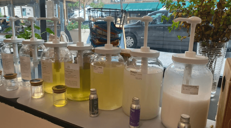 beberapa dispenser kaca yang ditata berjejer, berisi produk refill ramah lingkungan